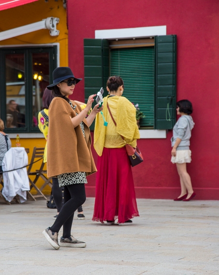 Several young ladies take selfies on the streets of Burano, Italy